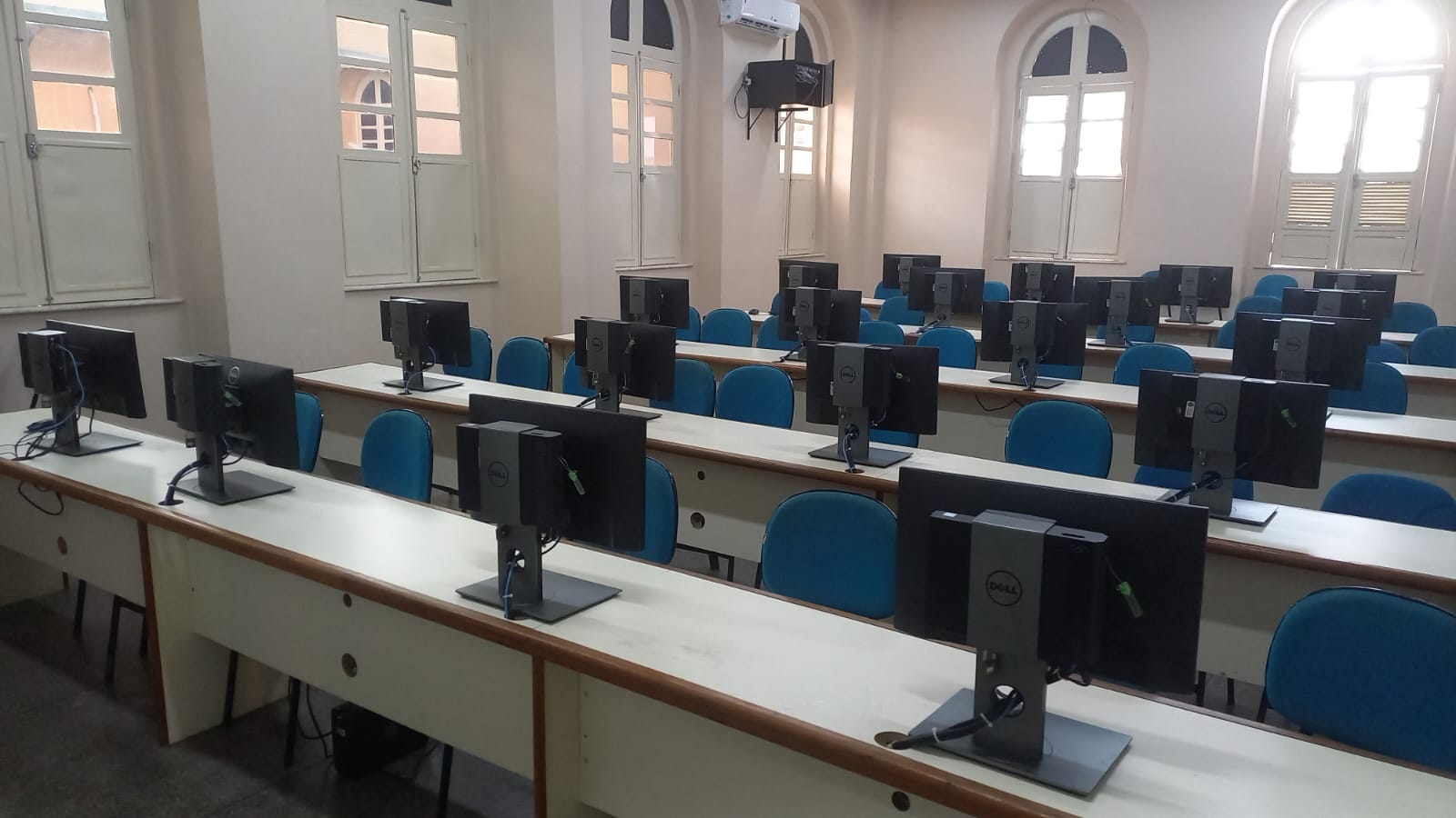 Laboratório de informática com bancadas e computadores